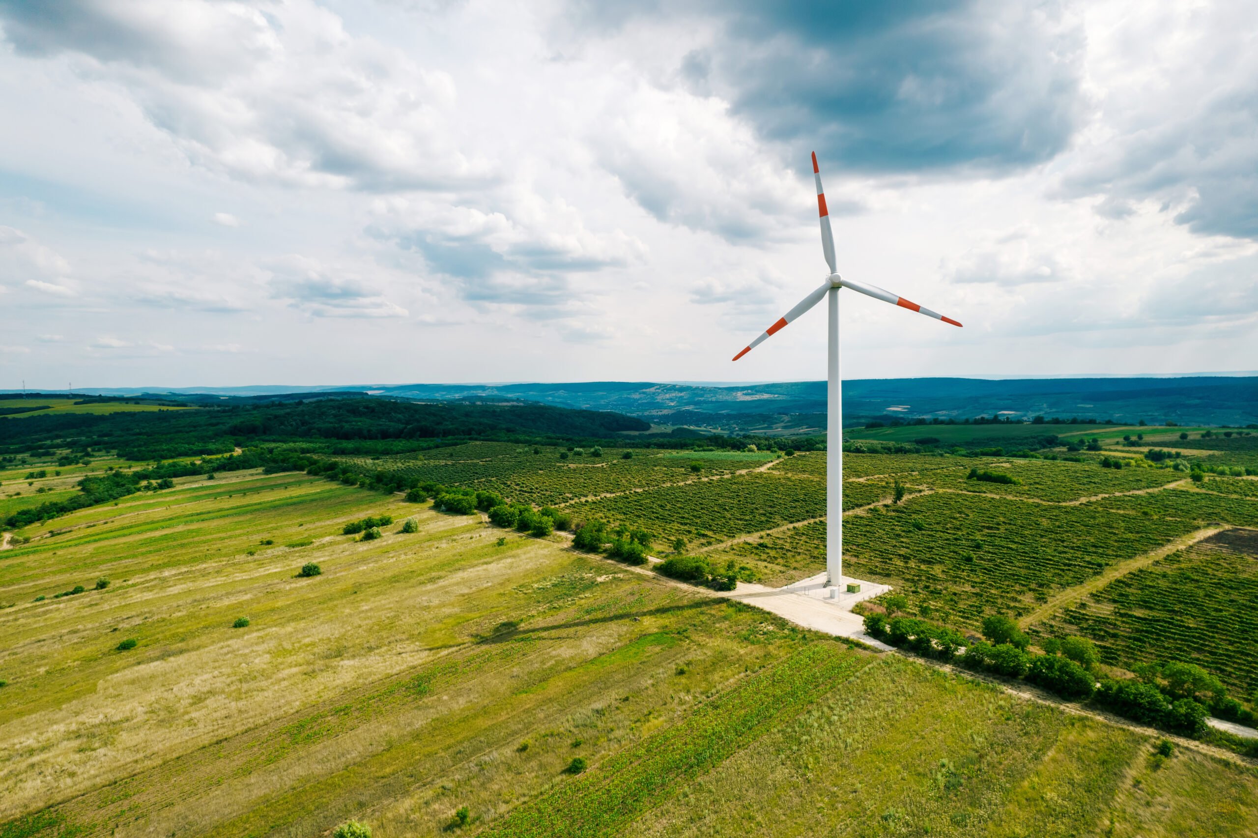 A working windmill in a field. Cloody weather, a lot of greenery around it